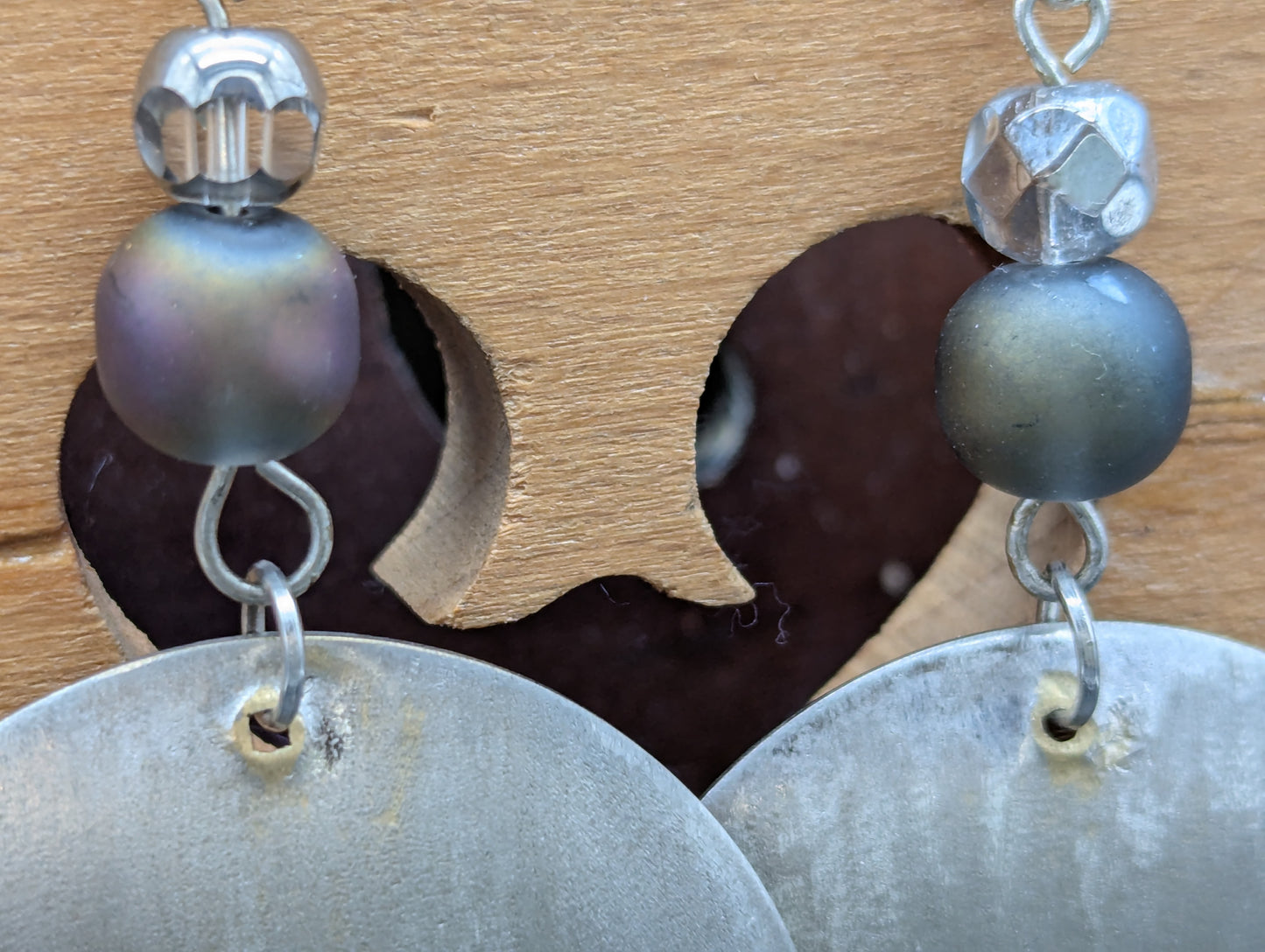 Close-up of a pair of silver earrings with blue opalescent beads.