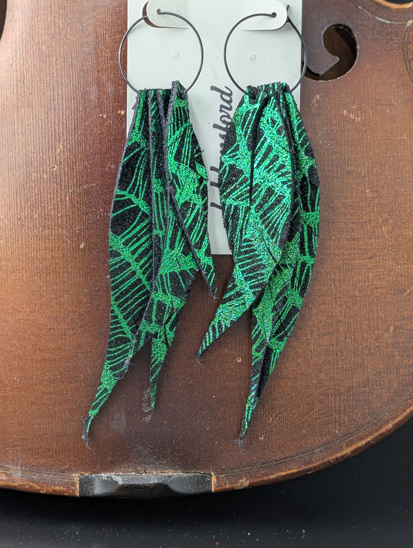 Leather earrings. Shiny green and black with black hoops. 5 inches long.