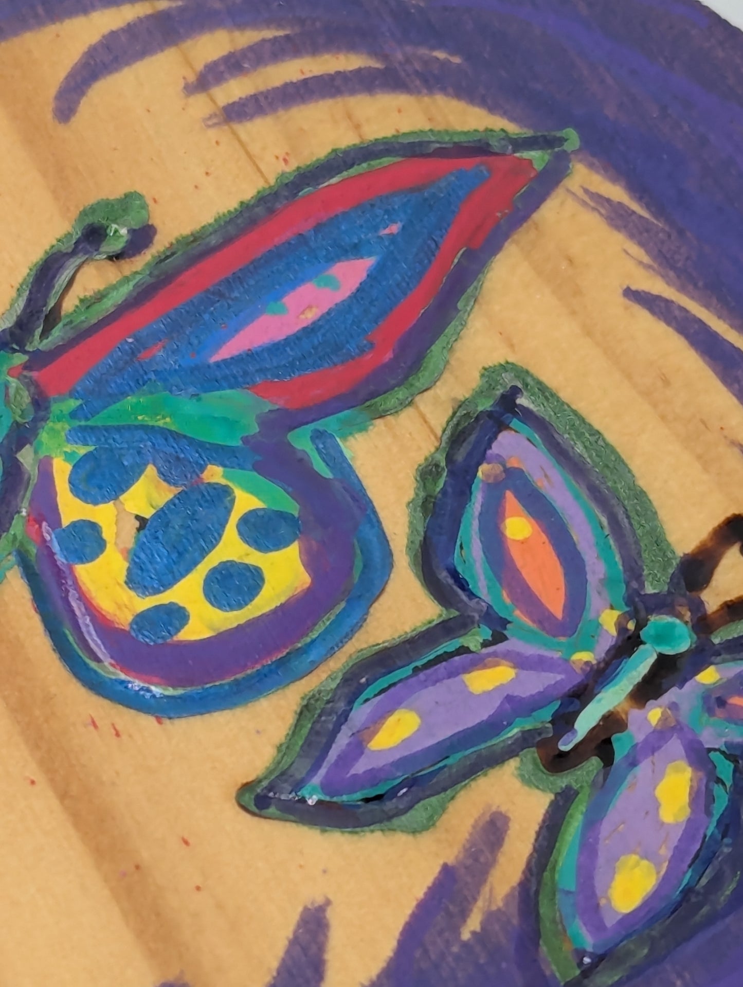 Close up of a wood burned and tole painted coaster with a butterfly design