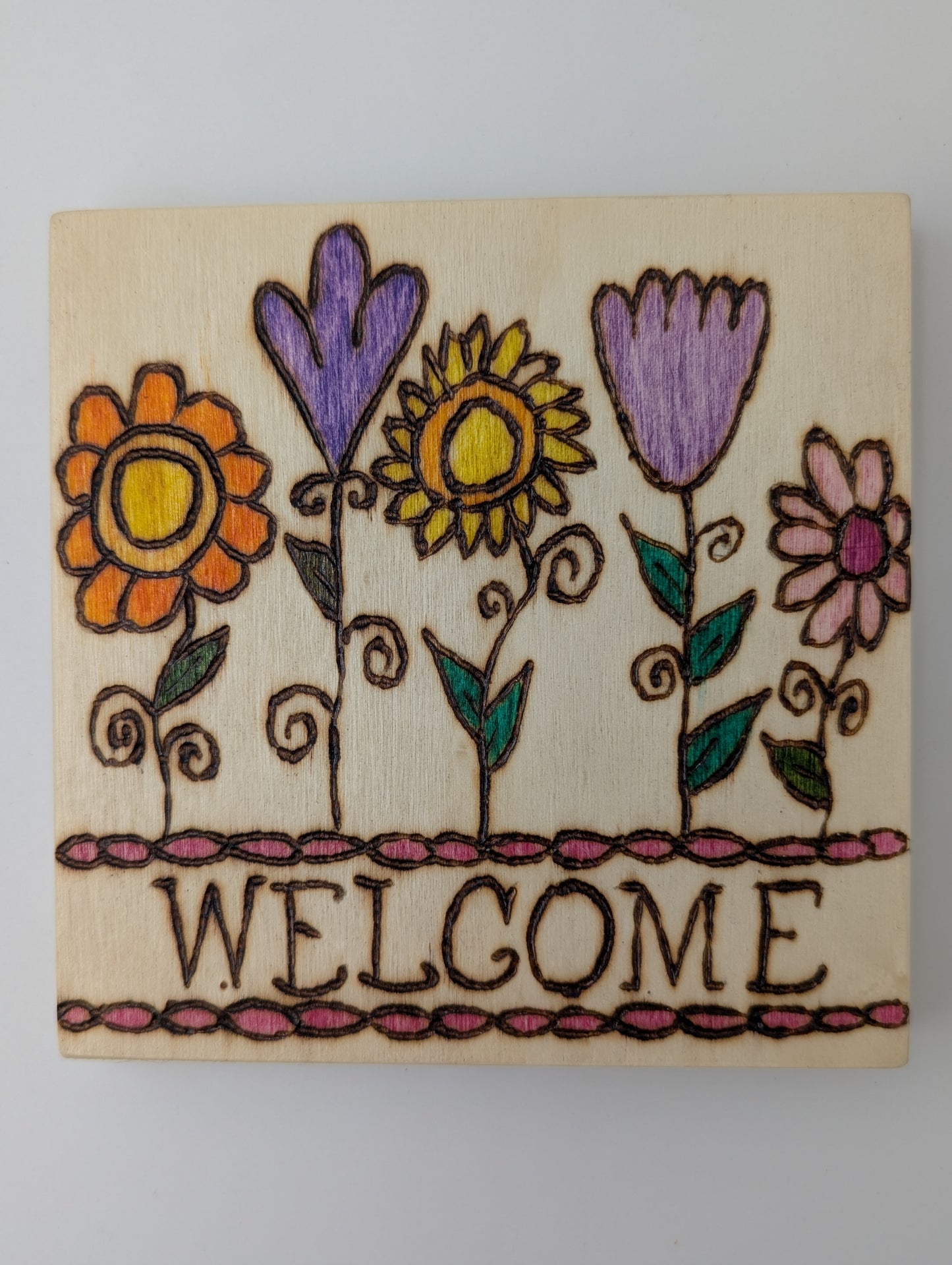 Original wooden plaque. Wood-burned and hand painted with colorful flowers and the word 'WELCOME' on a beige background.