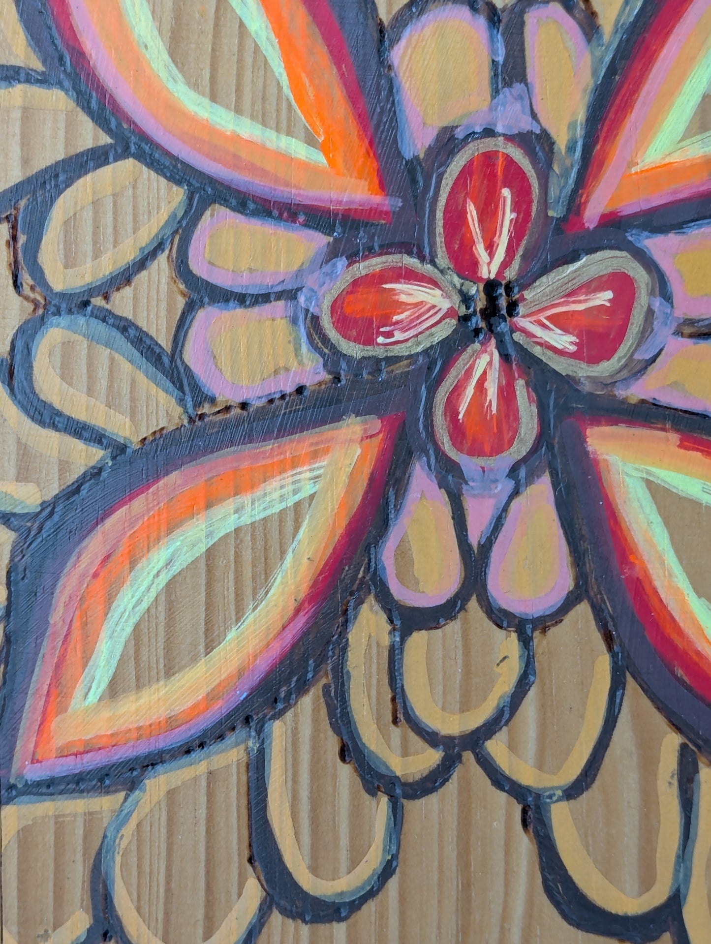 Close up of a decorative wooden cutting board with a wood burned and tole painted flower design and 3 cup hooks along the lower edge.
