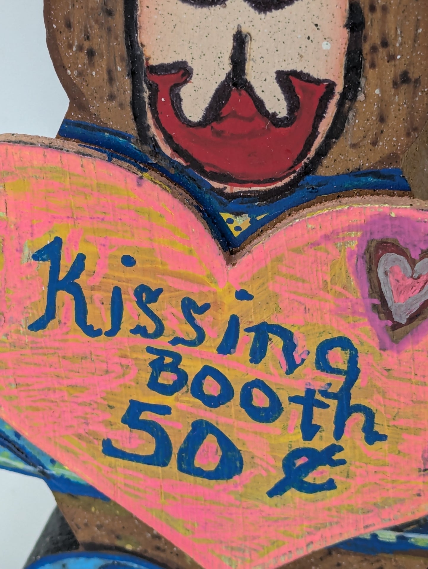 Close up of a wooden bear figurine with a heart-shaped sign saying 'Kissing Booth 50 Cents'