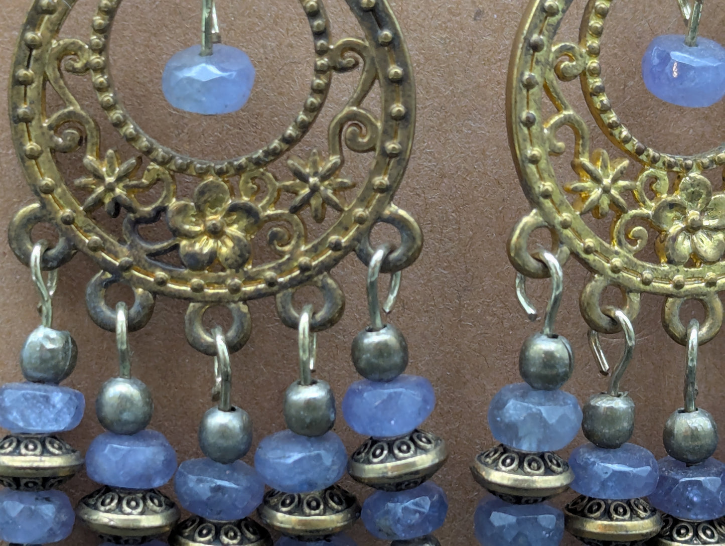 Close up of ornate antiqued gold earrings with labradorite gemstone beads.
