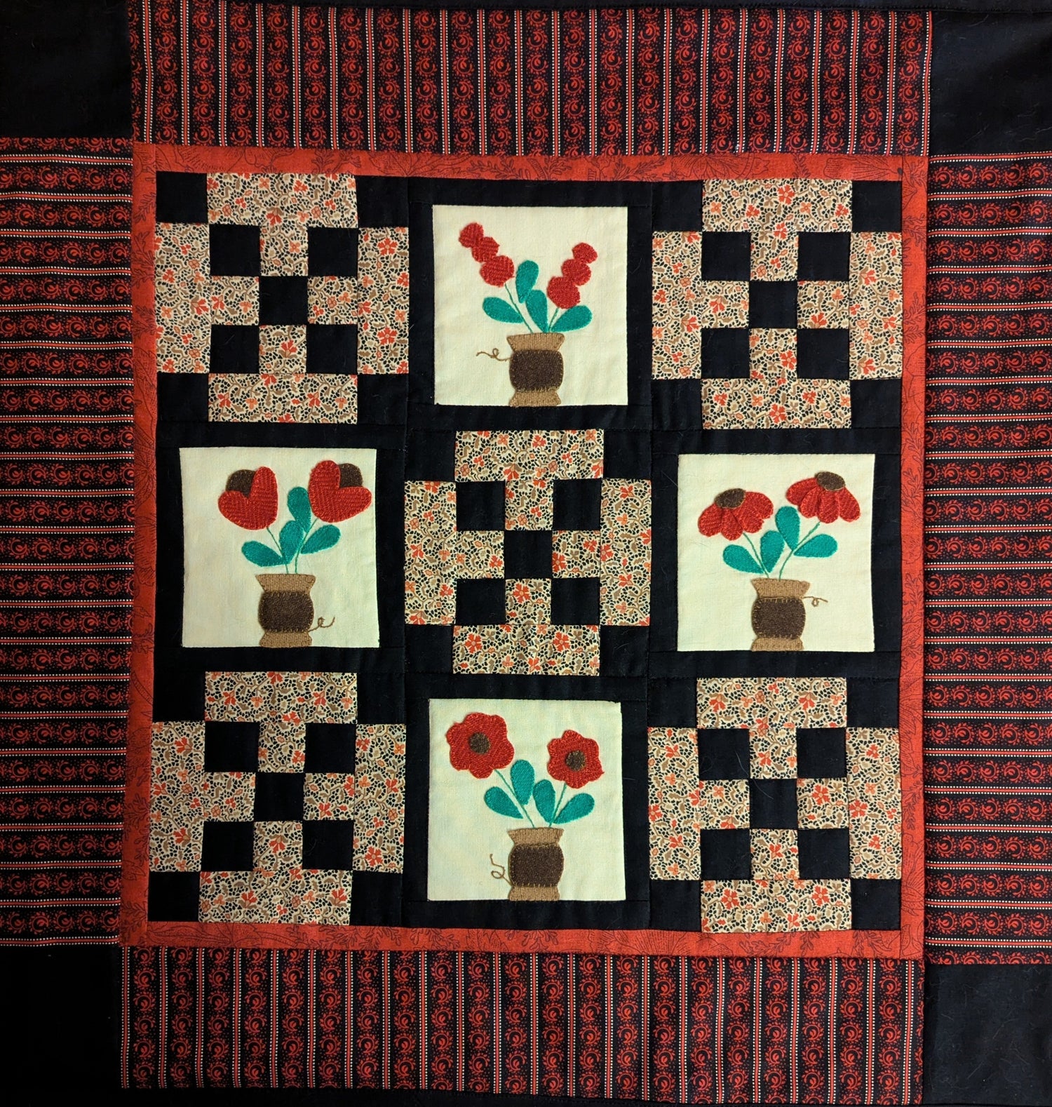Quilted wall hanging featuring bouquets and patchwork.