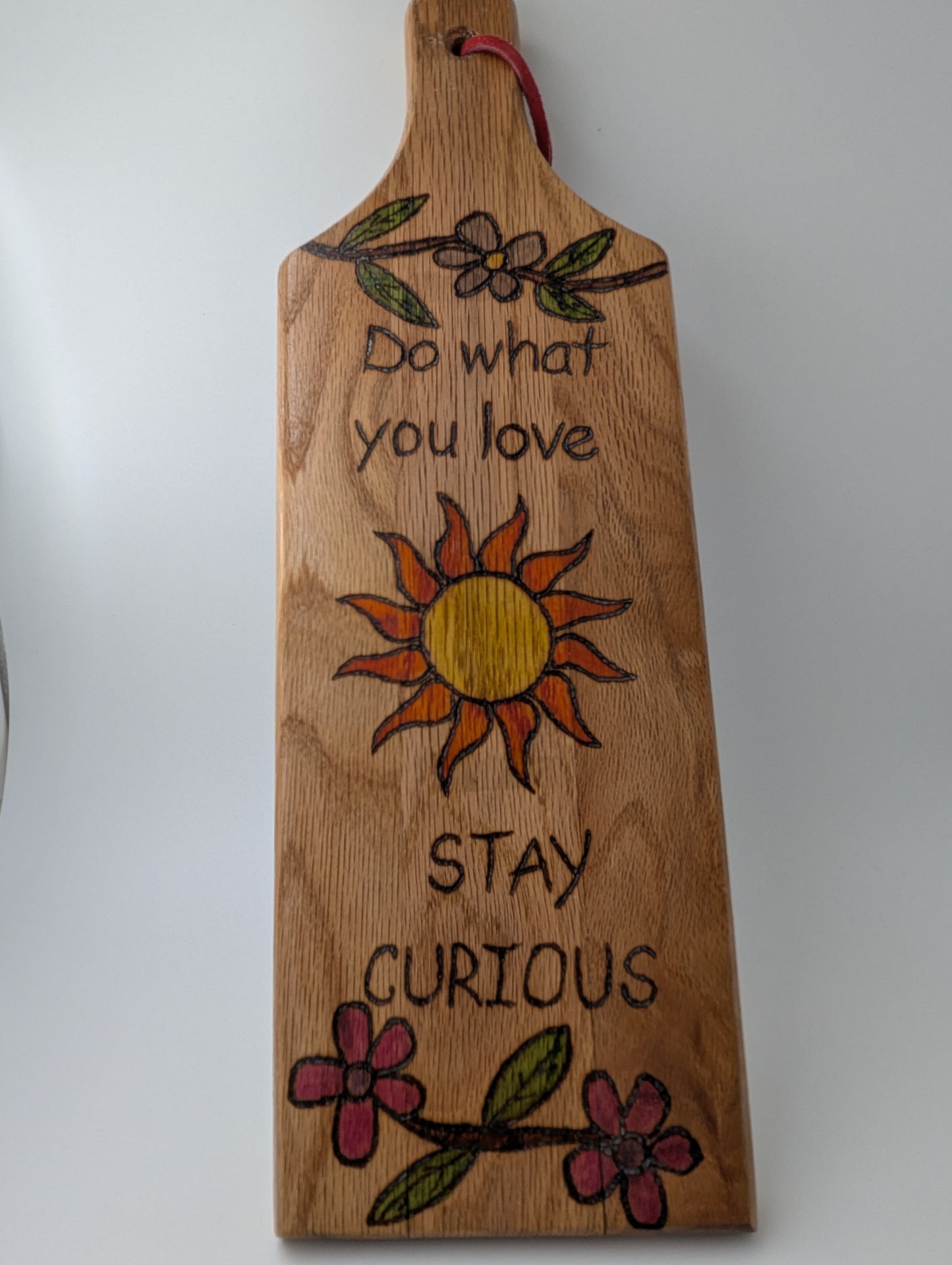 Original wood-burned and hand painted wooden paddle with 'Do What You Love Stay Curious' a sun and flowers.