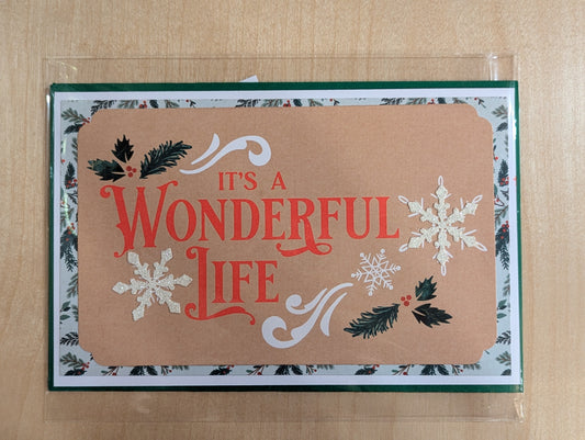 Christmas card with 'It's a Wonderful Life' text and snowflakes on a brown kraft paper background