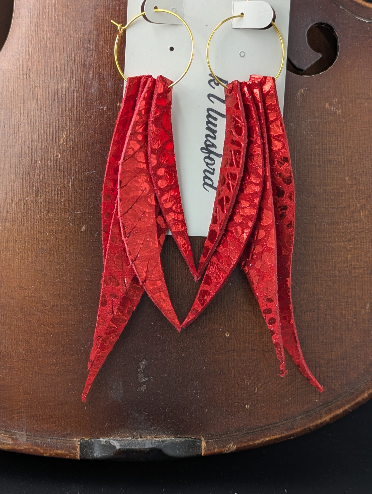 Leather leaf shaped earrings. Red with metallic red accents on gold hoops. 5 inches long.