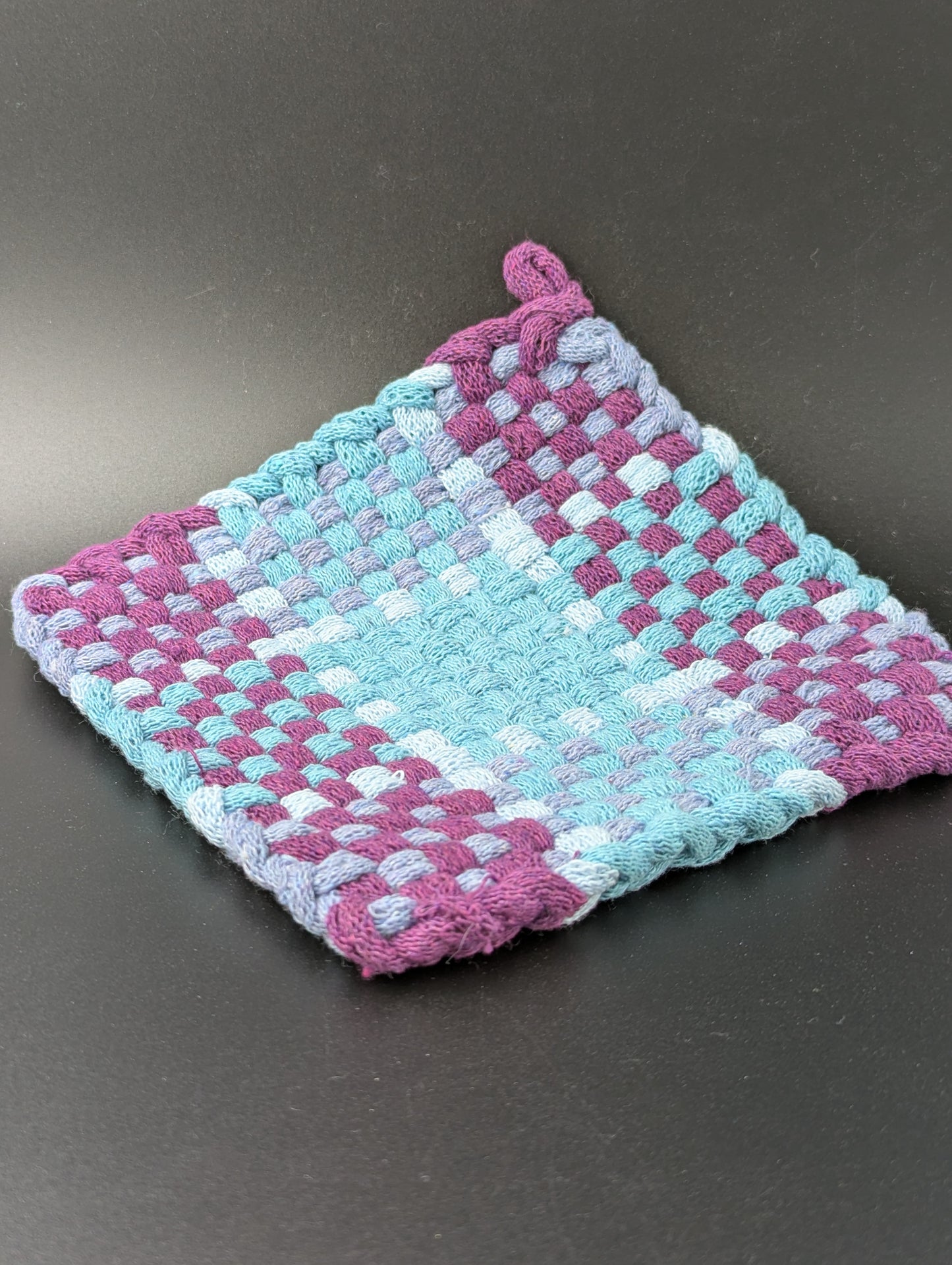 Hand woven pot holder in purple, blue and gray.