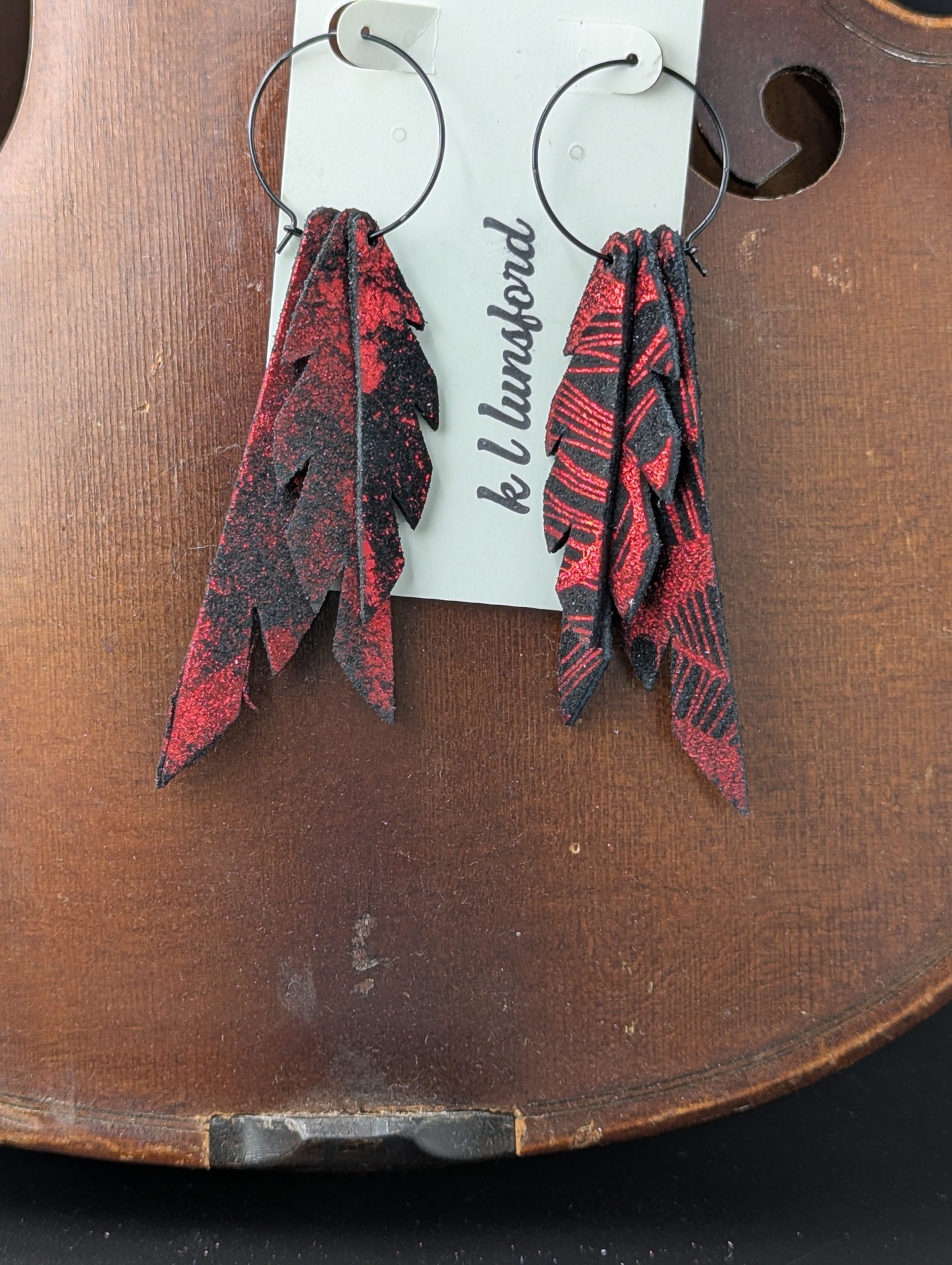 Leather earrings. Black with shimmery red on black hoops. 4 inches long.