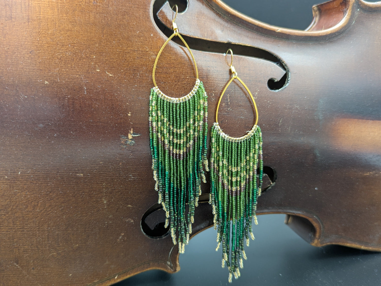 Green, gold, clear, purple, turquoise and silver glass seed beads trail down from a gold teardrop.