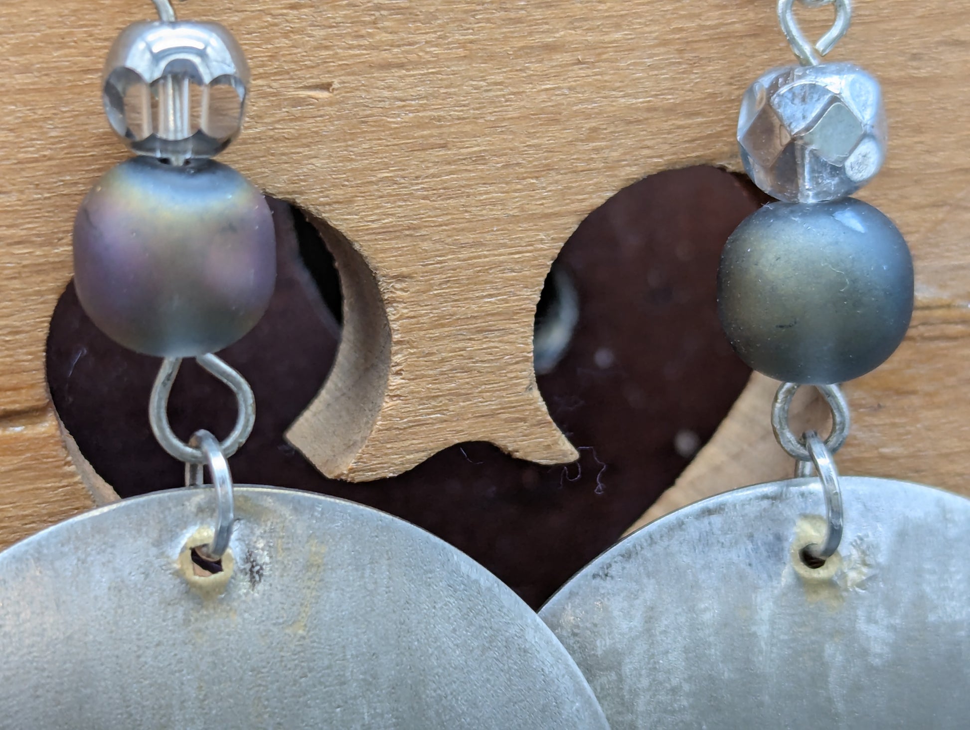 Close-up of a pair of silver earrings with blue opalescent beads.