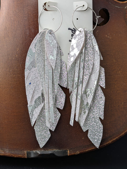 Vegan leather feather-shaped earrings. Sparkly silver and white with silver hoops, 5 inches in length