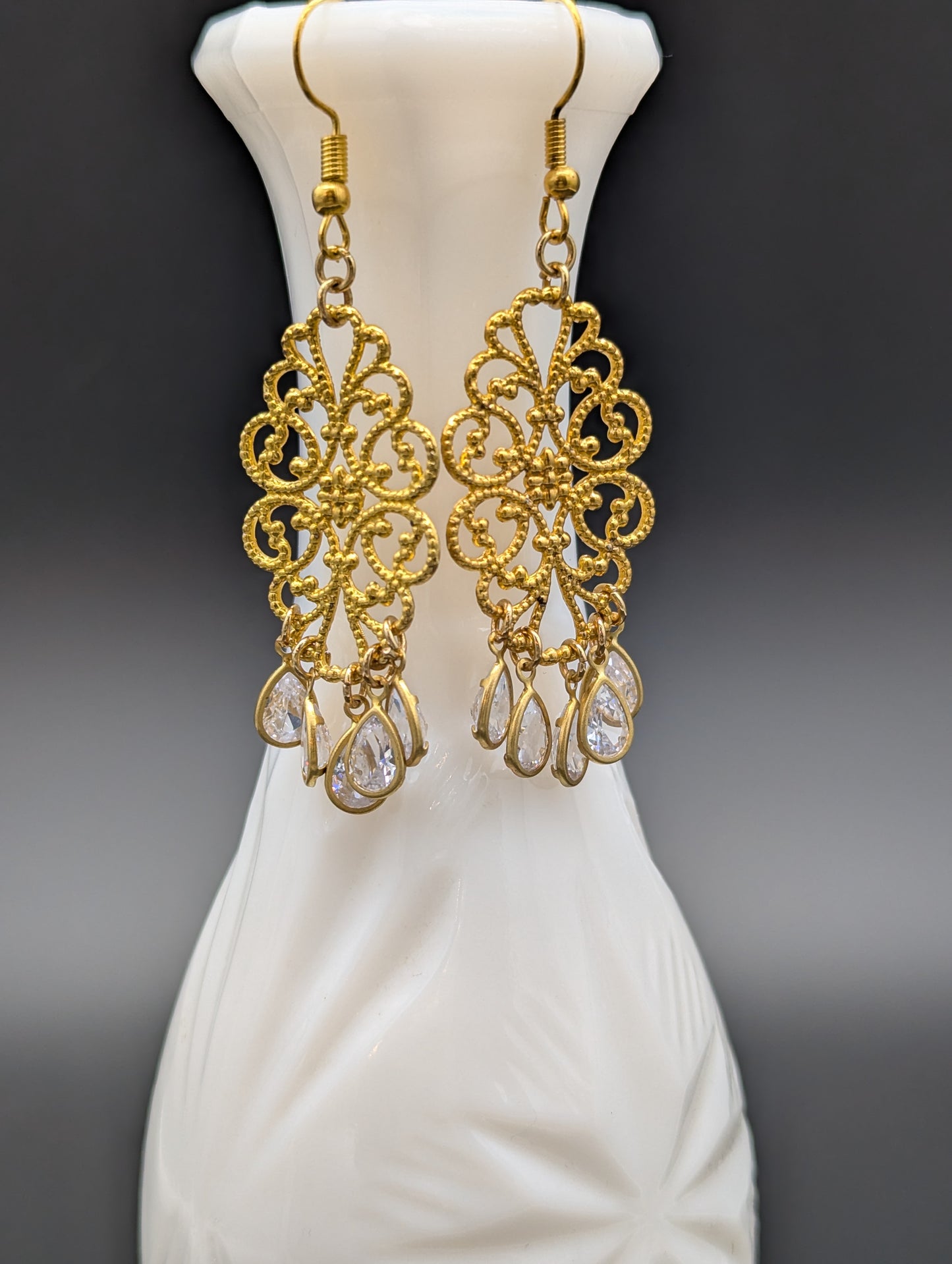 A set of golden filigree earrings with teardrop-shaped crystals.