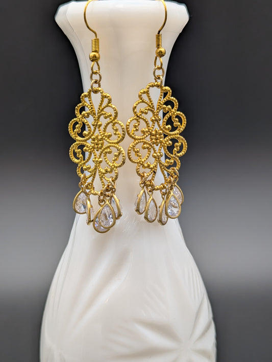 A set of golden filigree earrings with teardrop-shaped crystals.