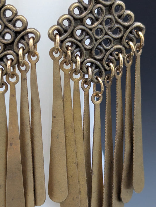 Close-up of a set of golden Celtic knot earrings with delicate metal drops. 