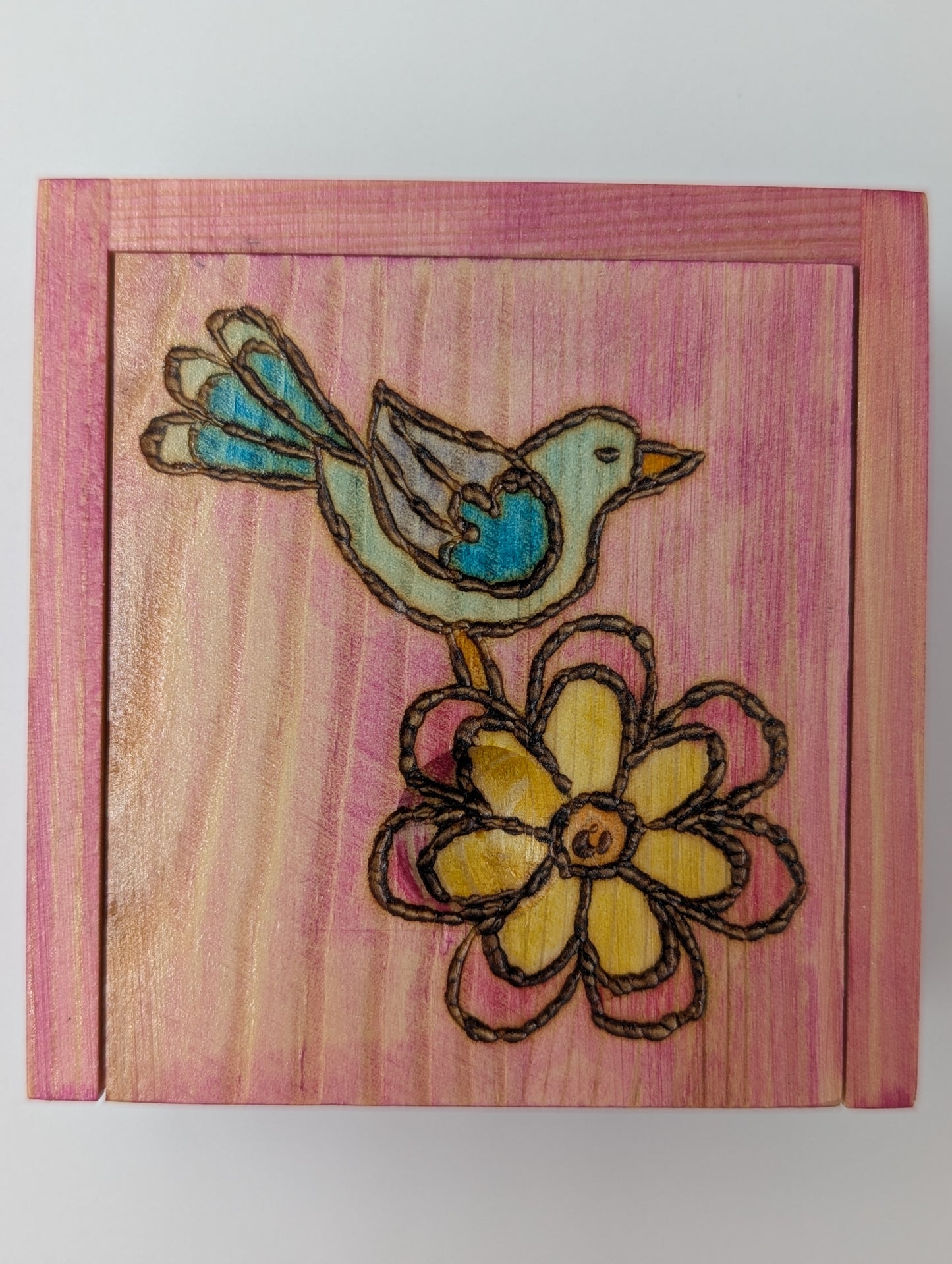 Wood-burned, hand painted wooden trinket box with a bluebird and flower on a pink background.