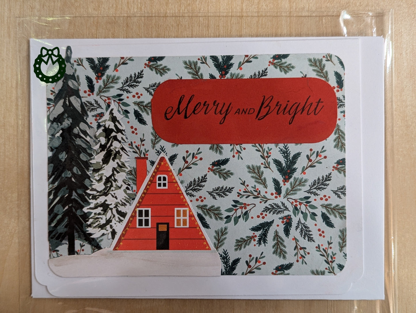 Christmas card with a red house, trees, and 'Merry and Bright' text on a patterned background.
