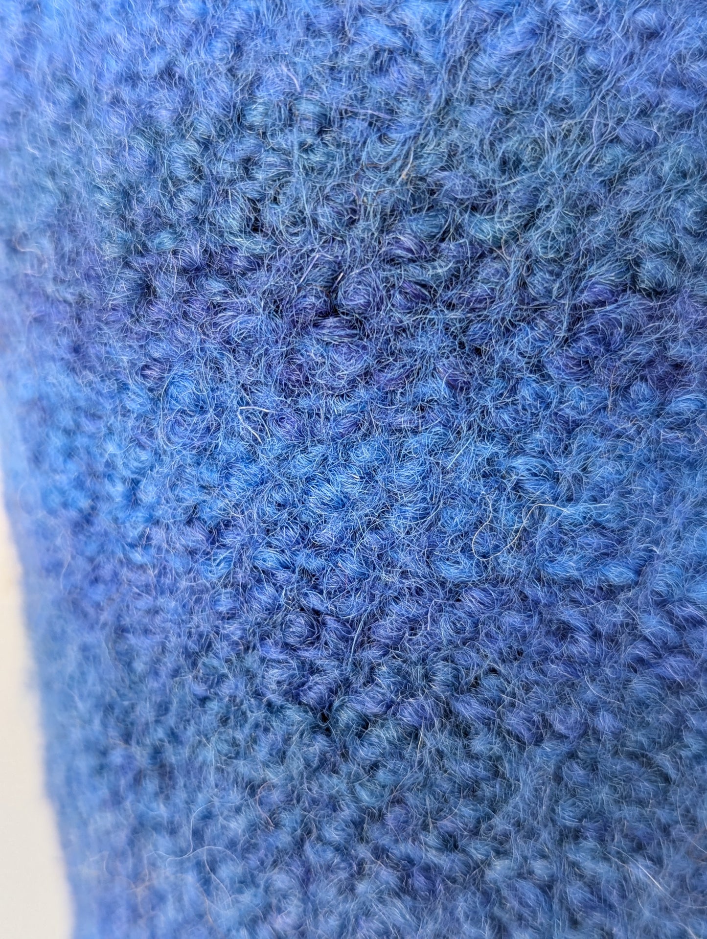 Close up of a blue knitted and felted mug cozy