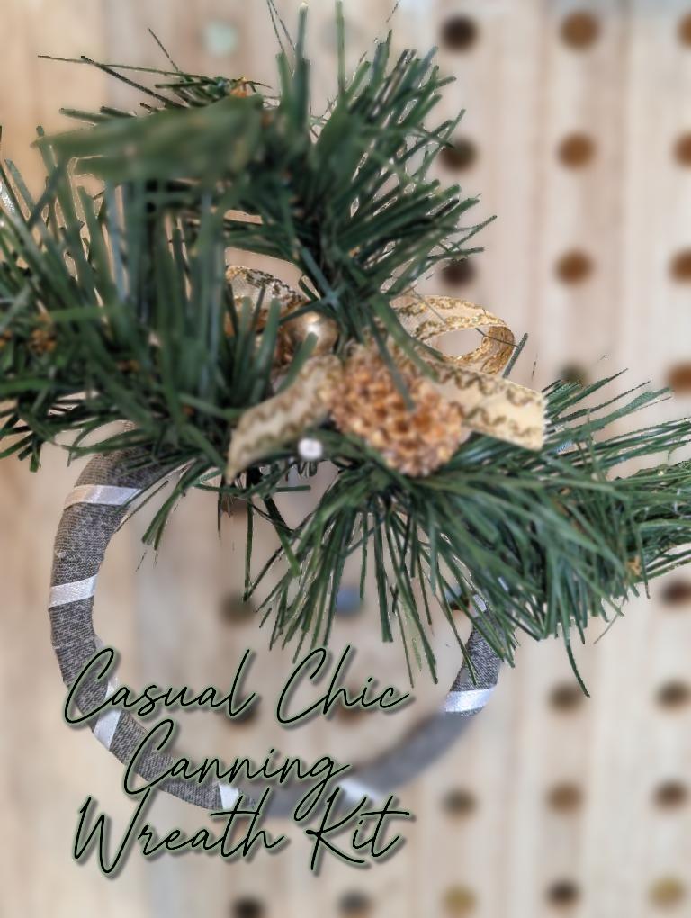Grey wreath with white ribbon decorated with gold ornaments nestled in faux pine branches and text 'Casual Chic Canning Wreath Kit' 