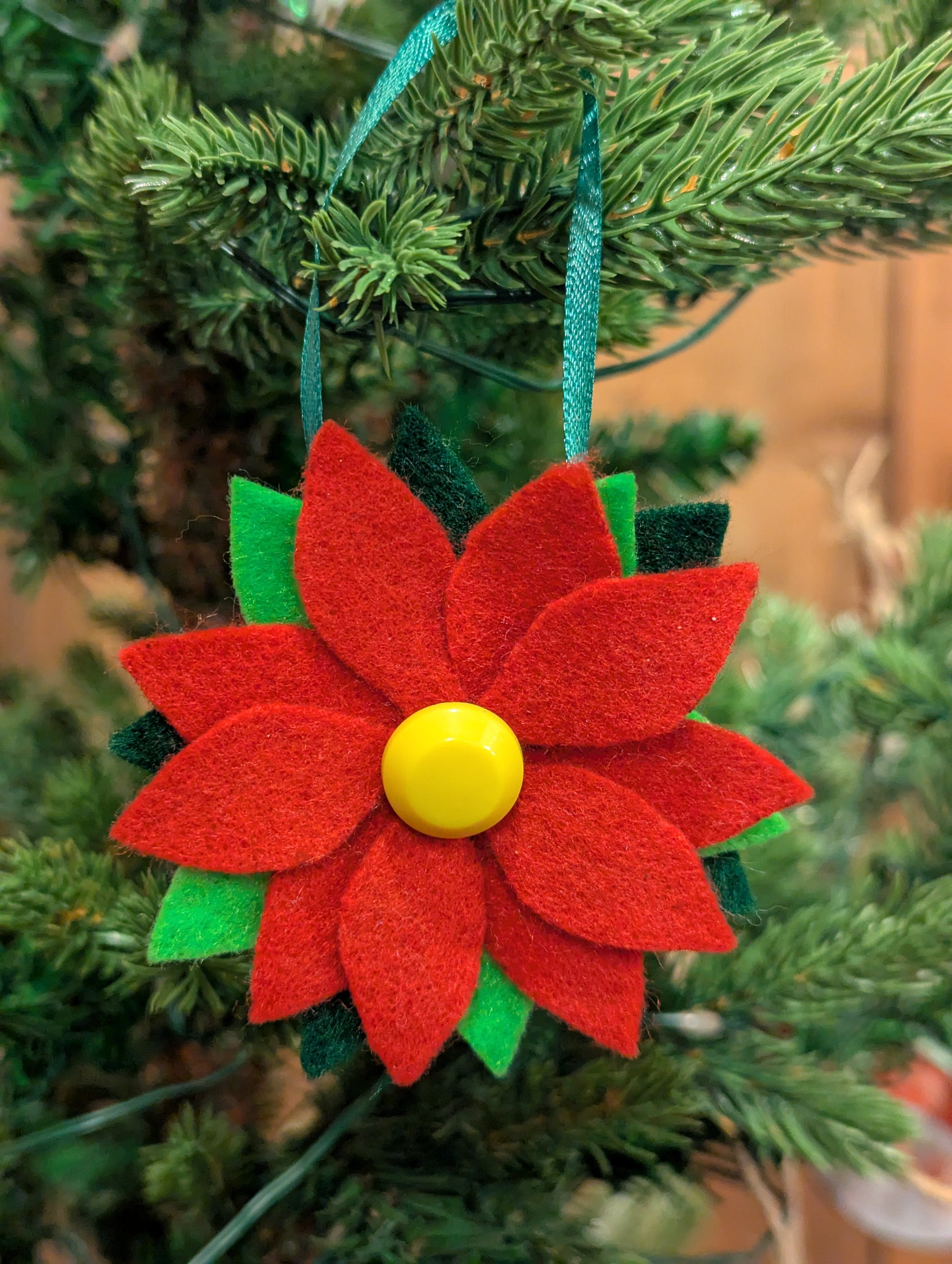 Red felt poinsettia flower ornament with a yellow button center.