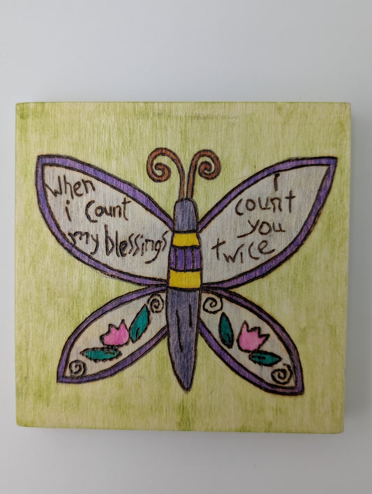 Wood-burned and hand painted wooden wall art. "When I count my blessings I count you twice" with image of butterfly and flowers.