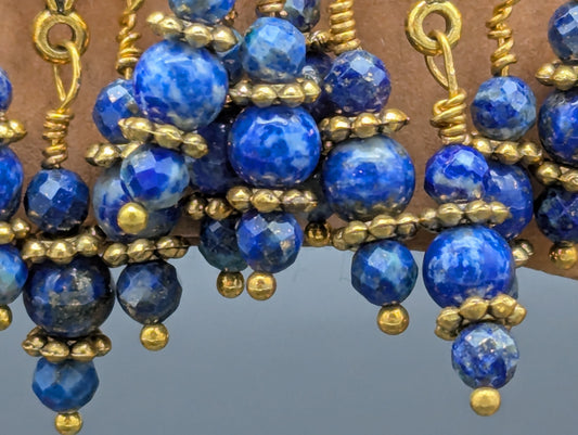 Close up of ornate blue and gold earrings.