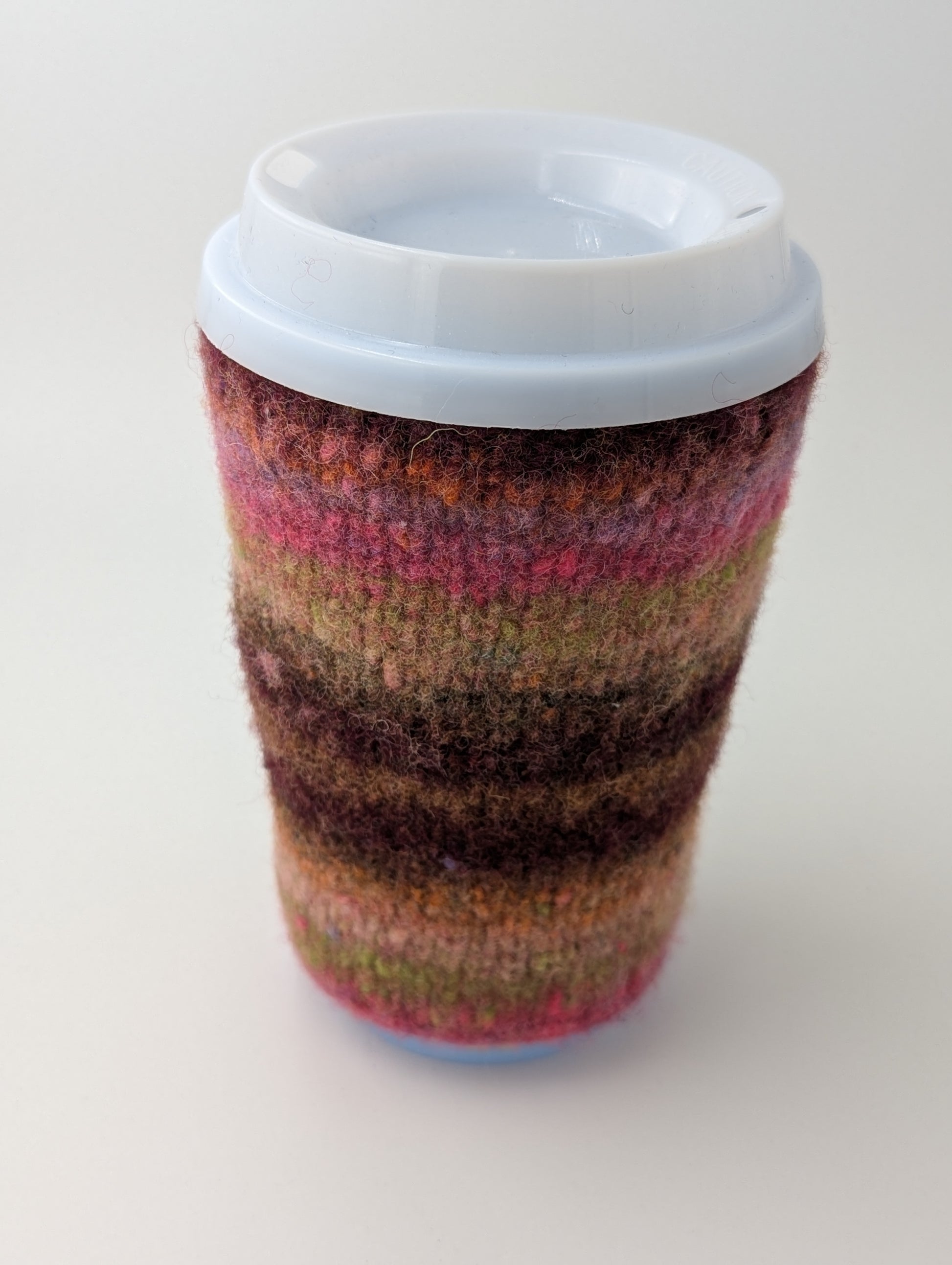 Striped knitted and felted mug cozy in shades of pink and brown