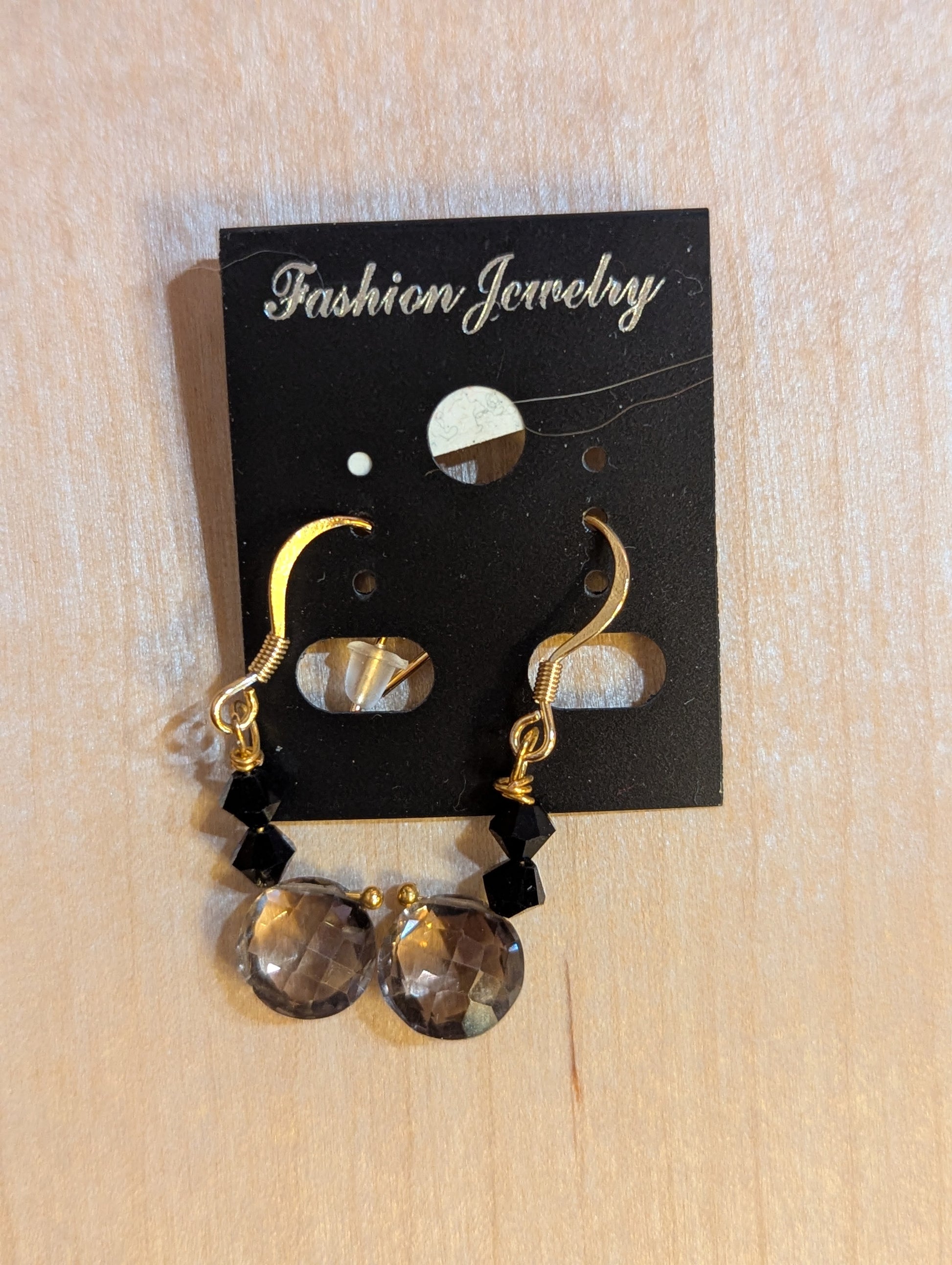 Dangle earrings with gold hook. Small black Swarovski crystals accent a smoked glass drop at the base of the earring.