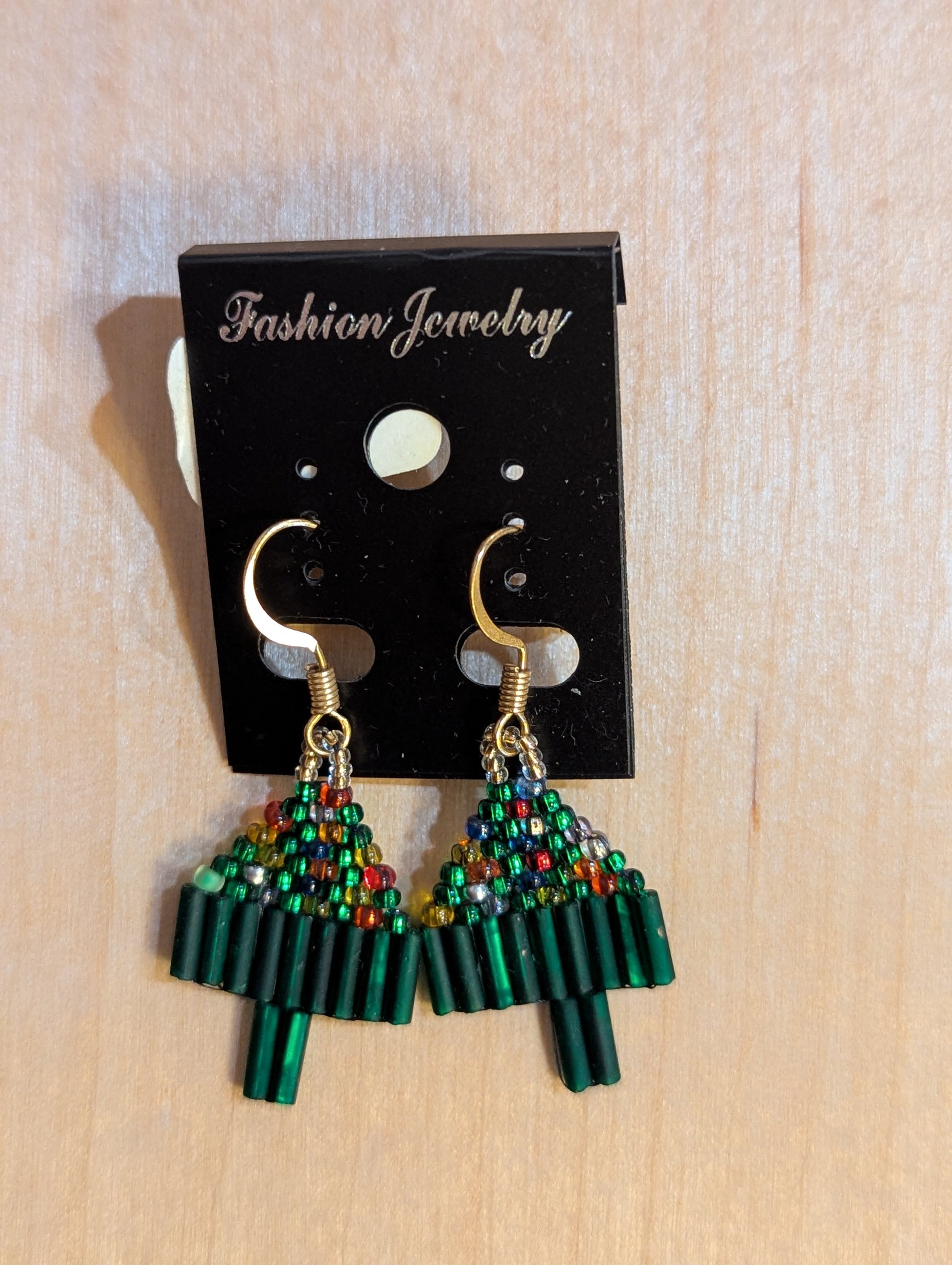 Dangle earrings on gold hooks with multicolored beads like lights and green beads for the lowest branches and trunks. 