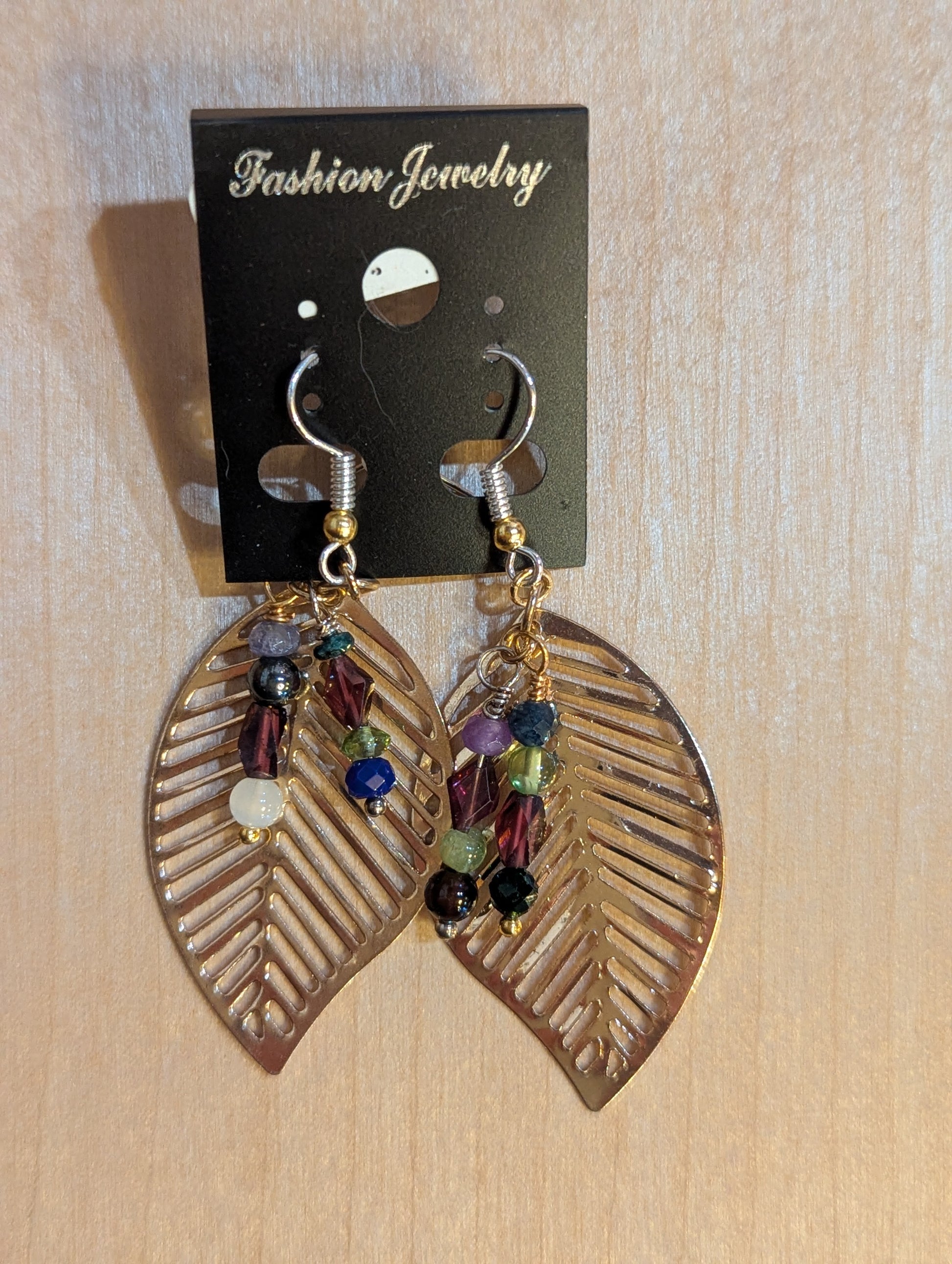 Dangle earrings on silver hooks with gold cut out leaves  accented with two strands of multicolor beads. 