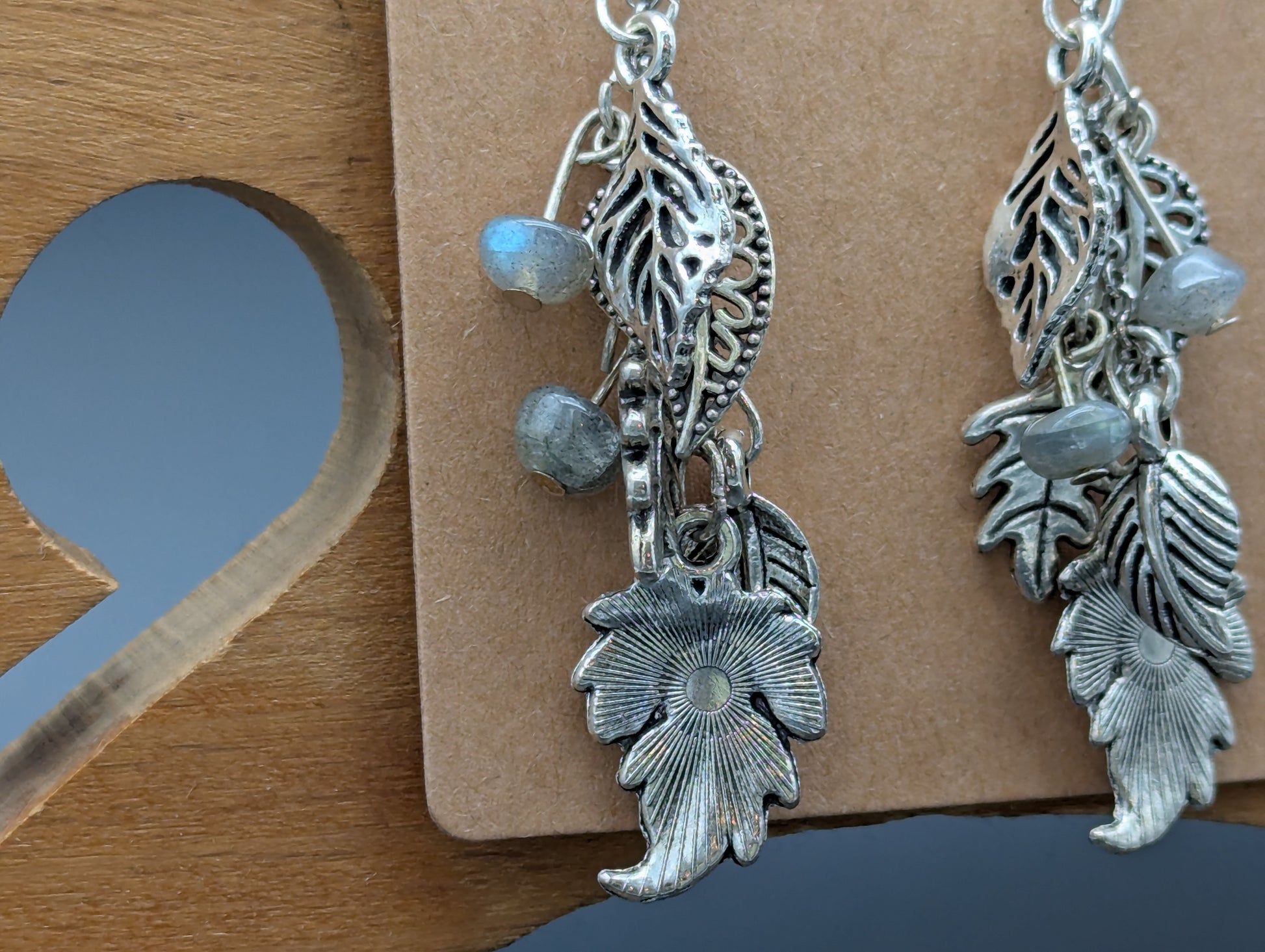 Close up of silver leaf earrings with labradorite gemstone accents.
