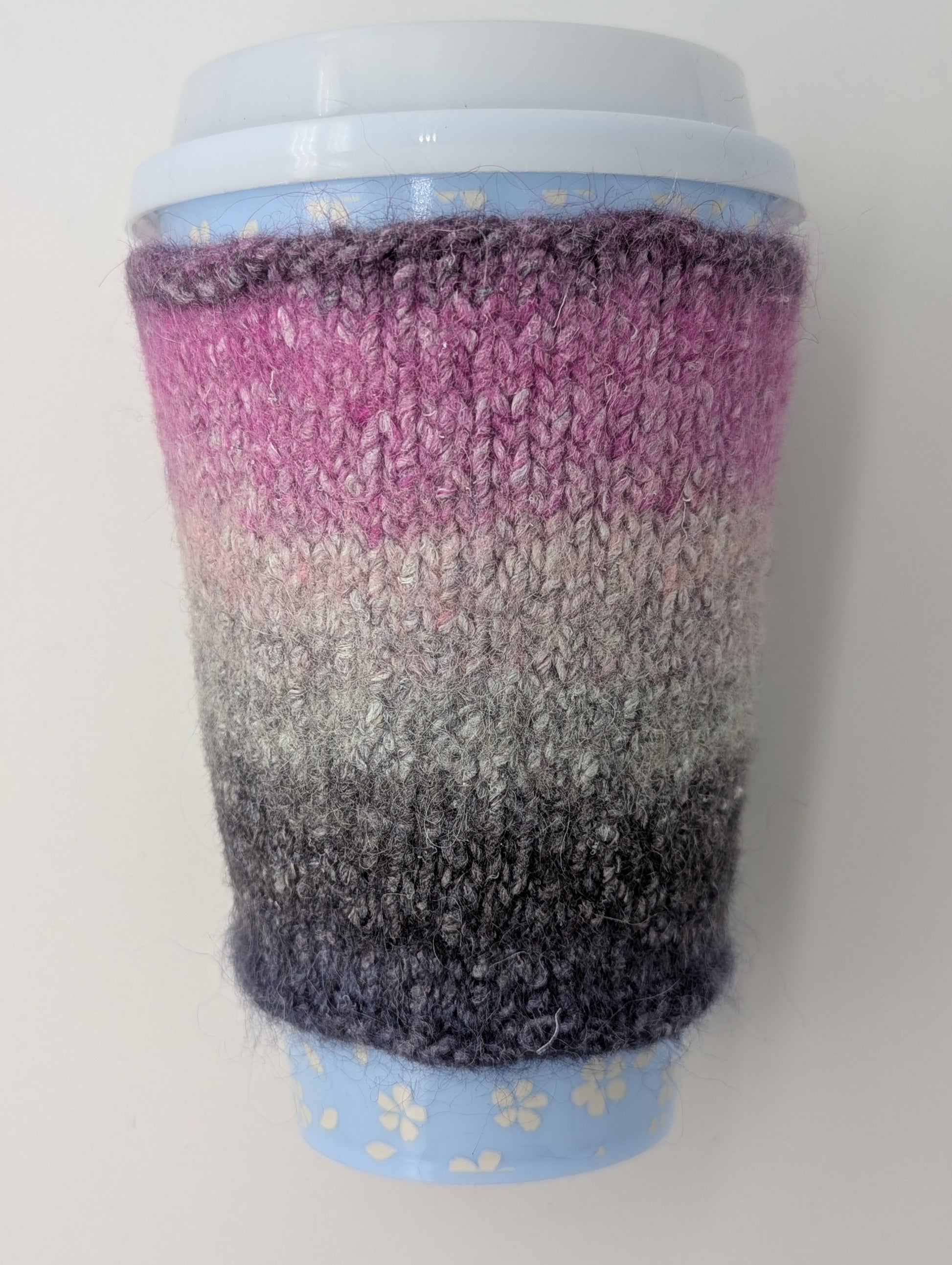 Knitted and felted mug cozy in shades of pink, beige, and grey