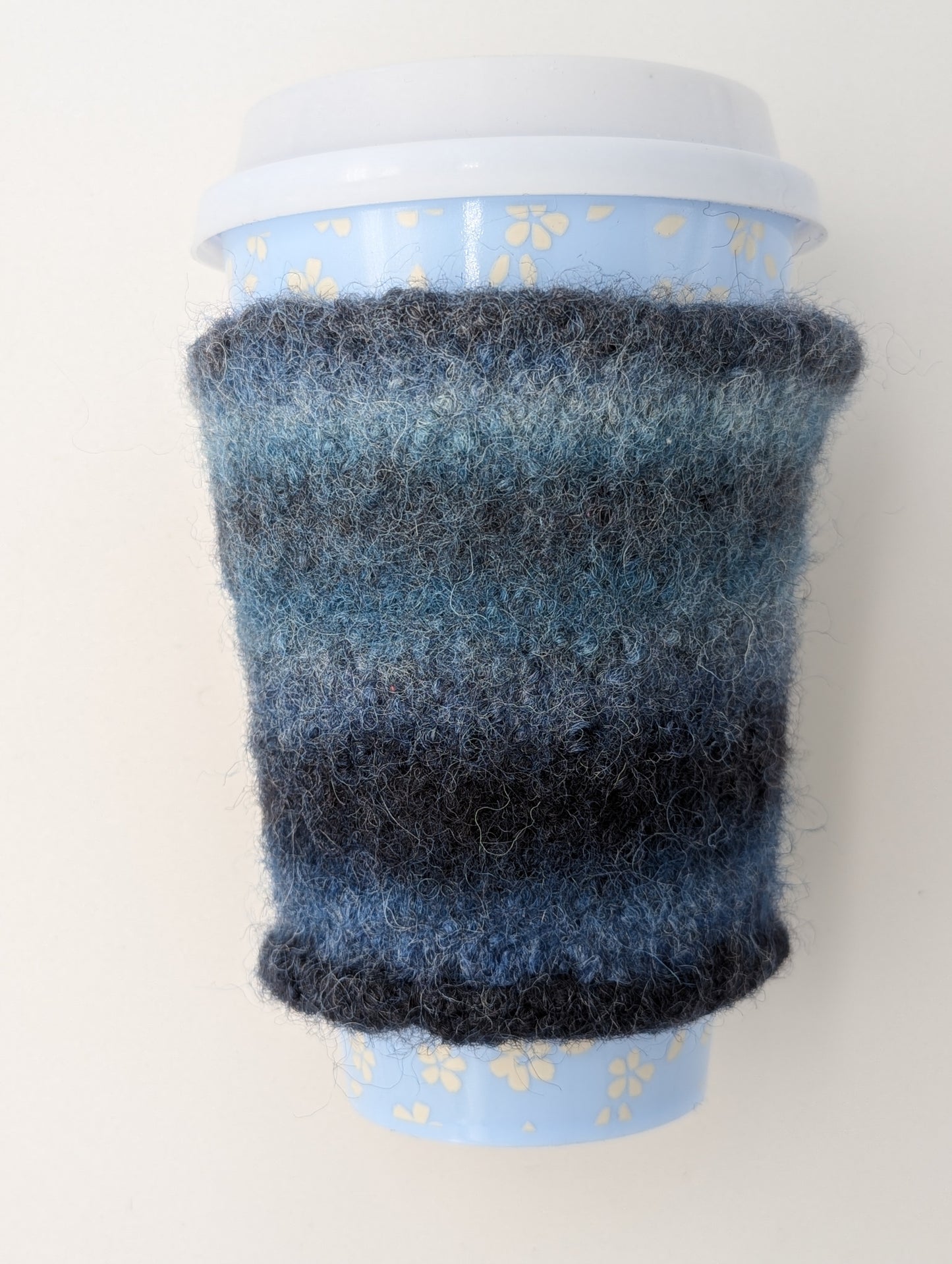 Knitted and felted mug cozy in shades of blue and grey