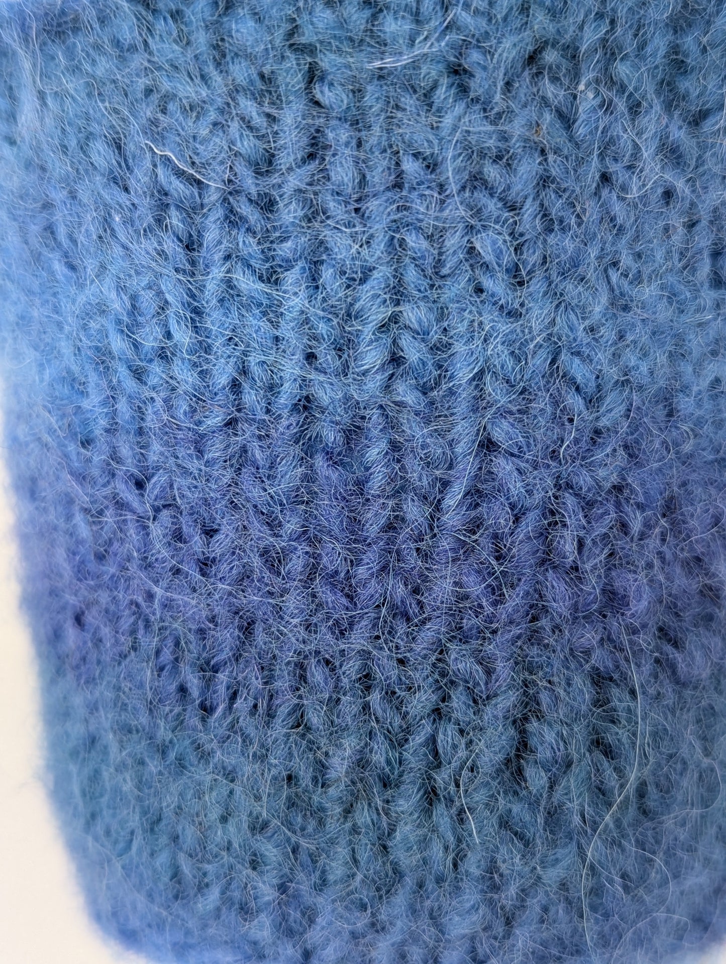 Close-up of a blue knitted and felted mug cozy 