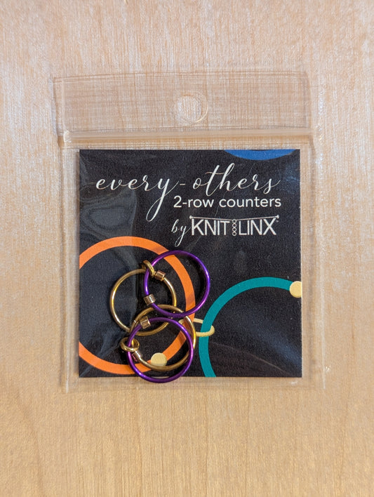 Packaged set of 'every-others' 2-row counters by KnitLinx for knitting needles size 9 through 13 in gold and purple colors