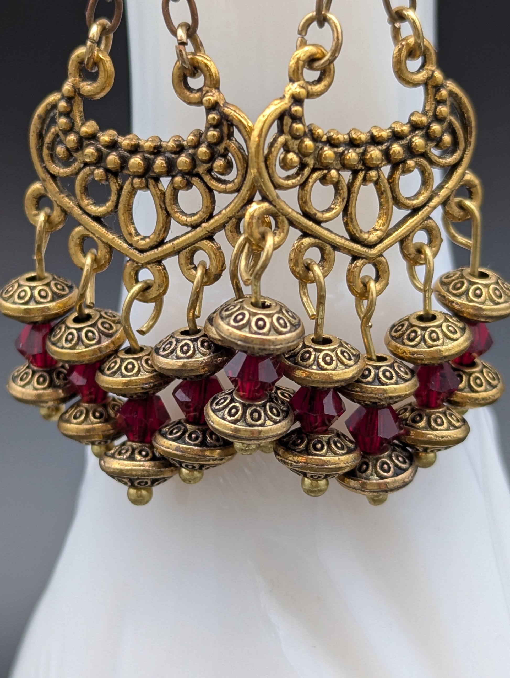 Close up of a set of elegant gold earrings with red Swarovski crystal beads.