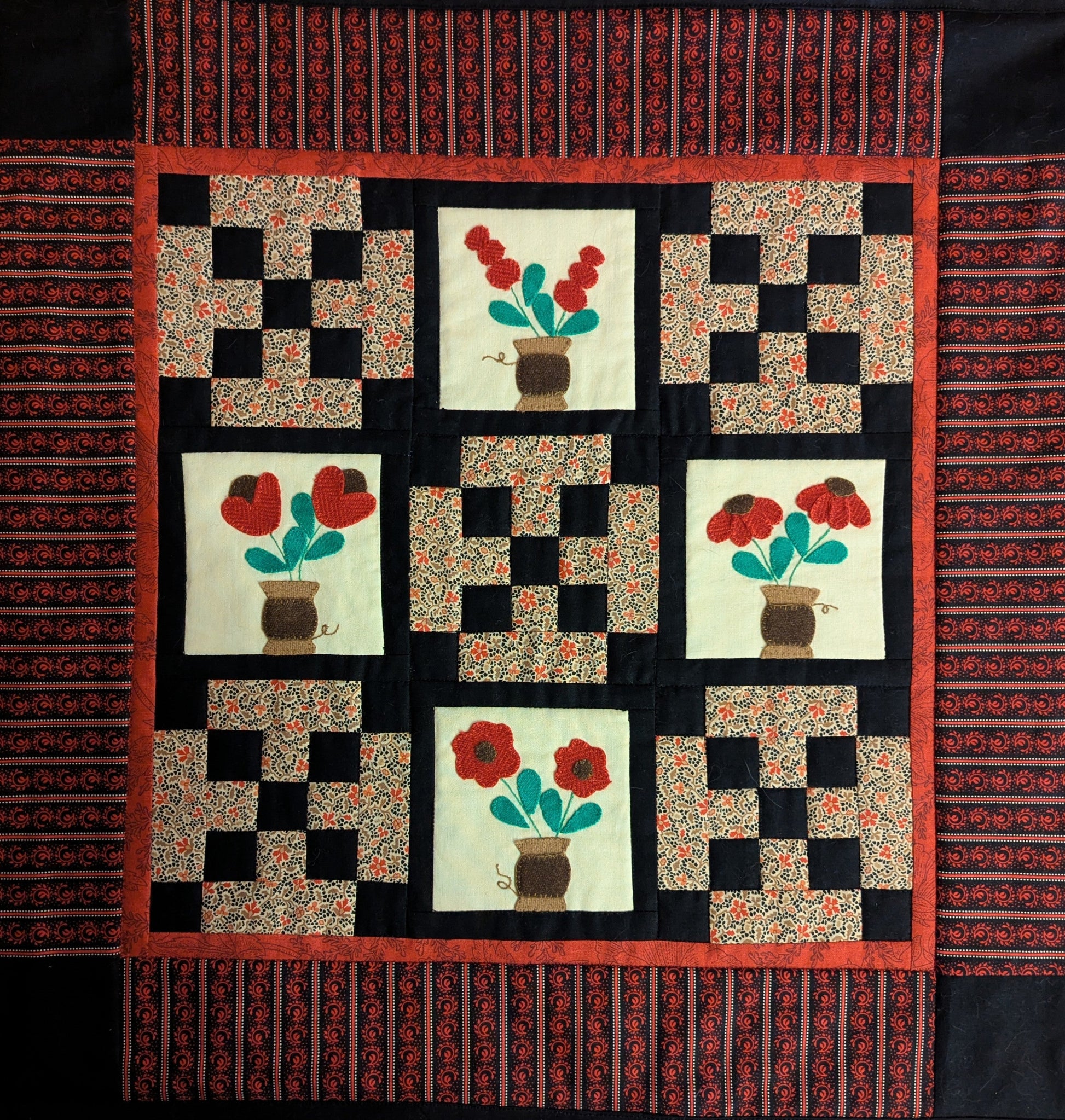Quilted wall hanging featuring bouquets and patchwork.
