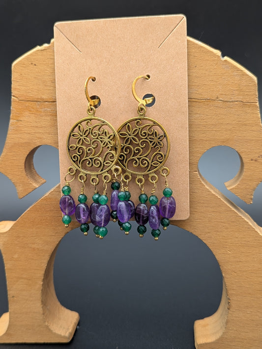 Earrings with gold floral patterns set off by amethyst gemstones and green Swarovski crystal beads.