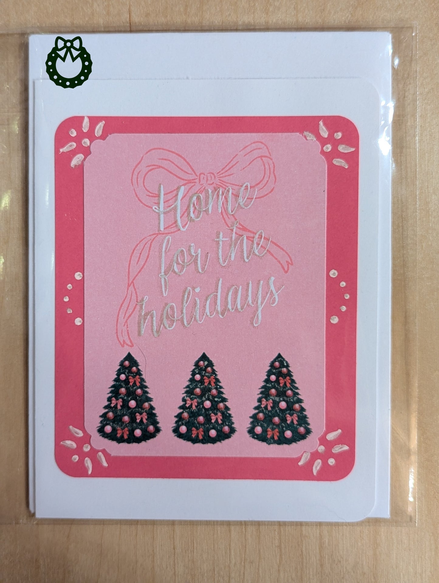 Greeting card with 'Home for the holidays' text and Christmas trees on a pink background.