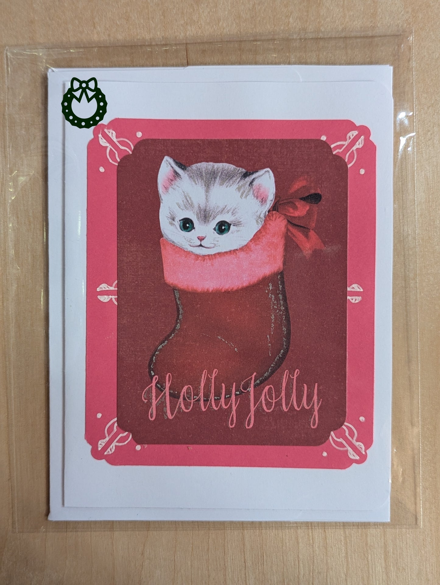 Greeting card with a cat in a red stocking and 'Holly Jolly' text on a pink border.