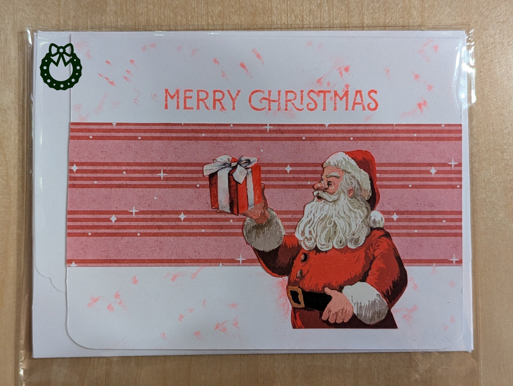 Christmas card with Santa Claus holding a gift on a red and white striped background.