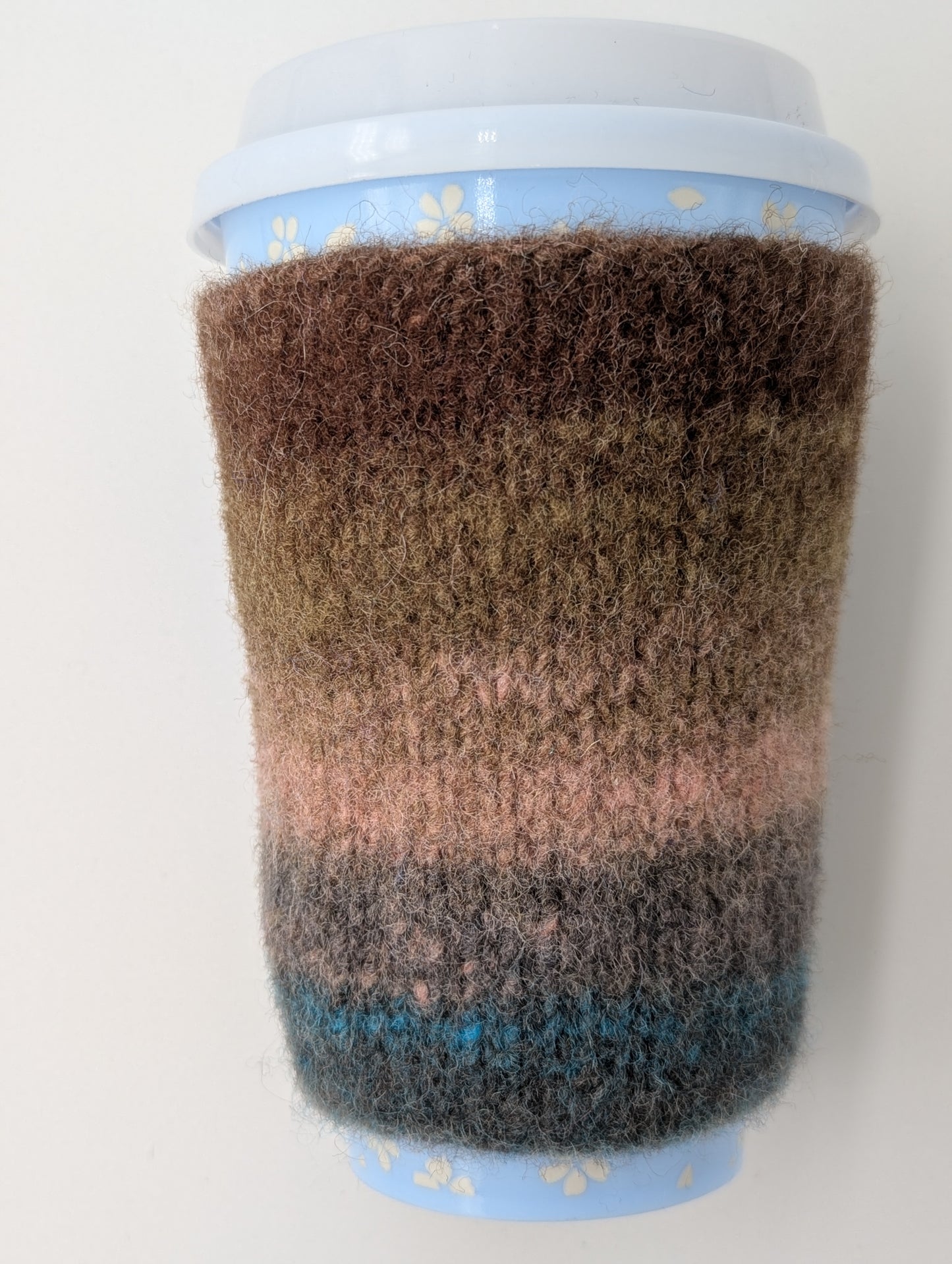 Knitted and felted mug cozy with a brown to blue color gradient