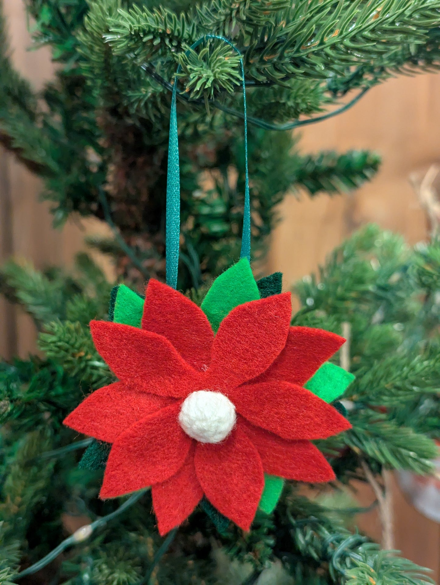 Red felt poinsettia flower ornament with a snowball in the center.