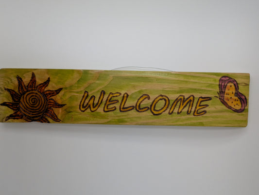 Original wood-burned and hand painted wooden sign with 'WELCOME' text, sun, and butterfly design. Wire hanger to attach to a wall or post.