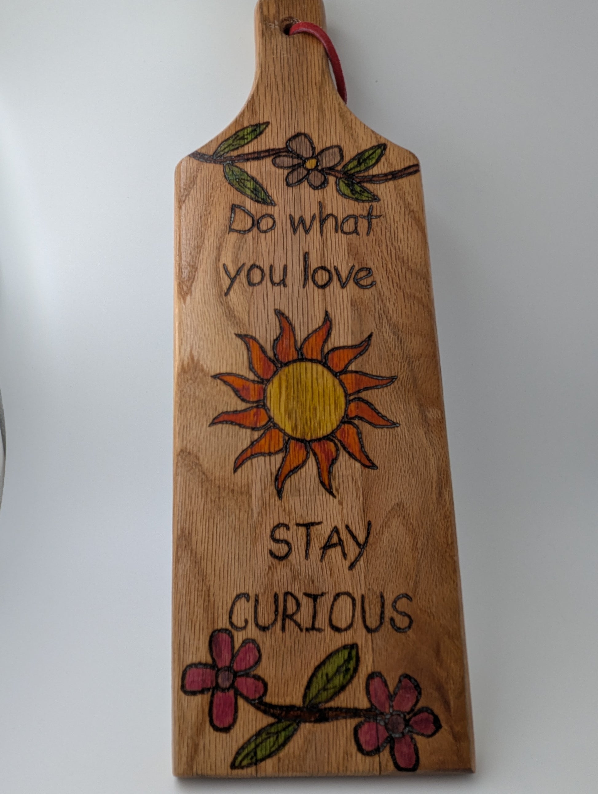 Original wood-burned and hand painted wooden paddle with 'Do What You Love Stay Curious' a sun and flowers.