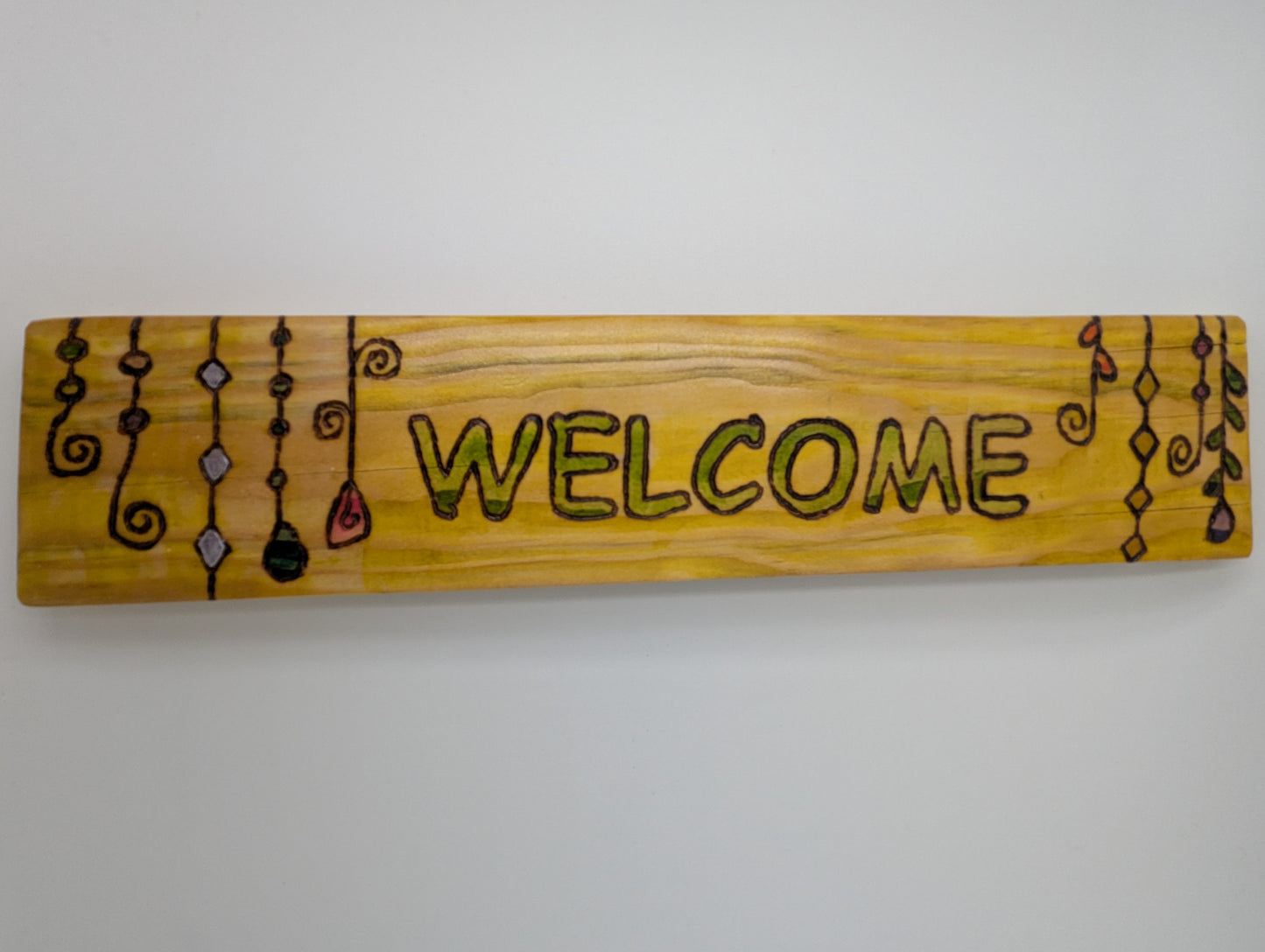 Wood-burned and hand painted wooden sign with 'WELCOME' text and decorative suncatchers.