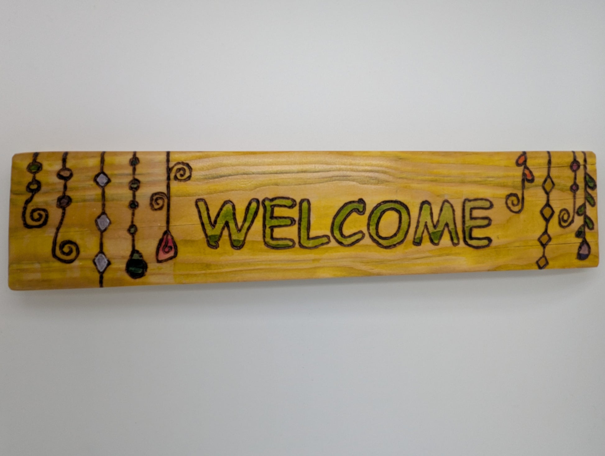 Wood-burned and hand painted wooden sign with 'WELCOME' text and decorative suncatchers.