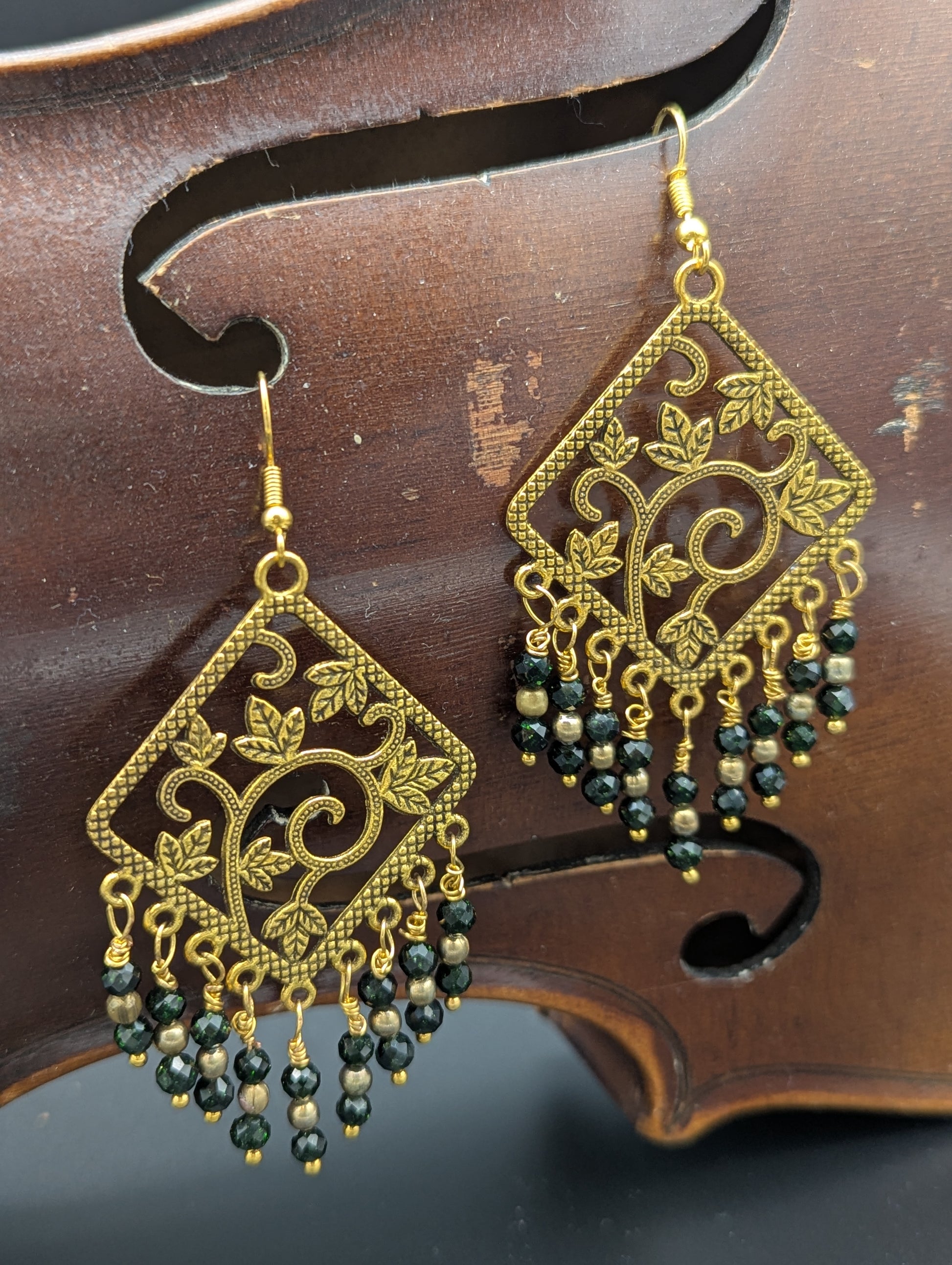Earrings decorated with golden vines and richly luminous green Swarovski crystals and gold tone pearl seed beads