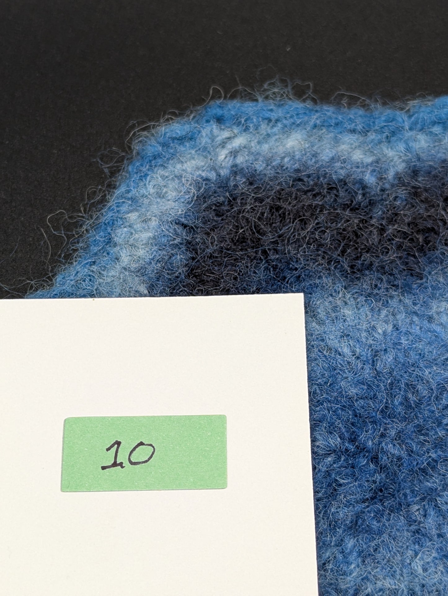 Close up of a blue hand knitted and felted coaster. This coaster is number 10.