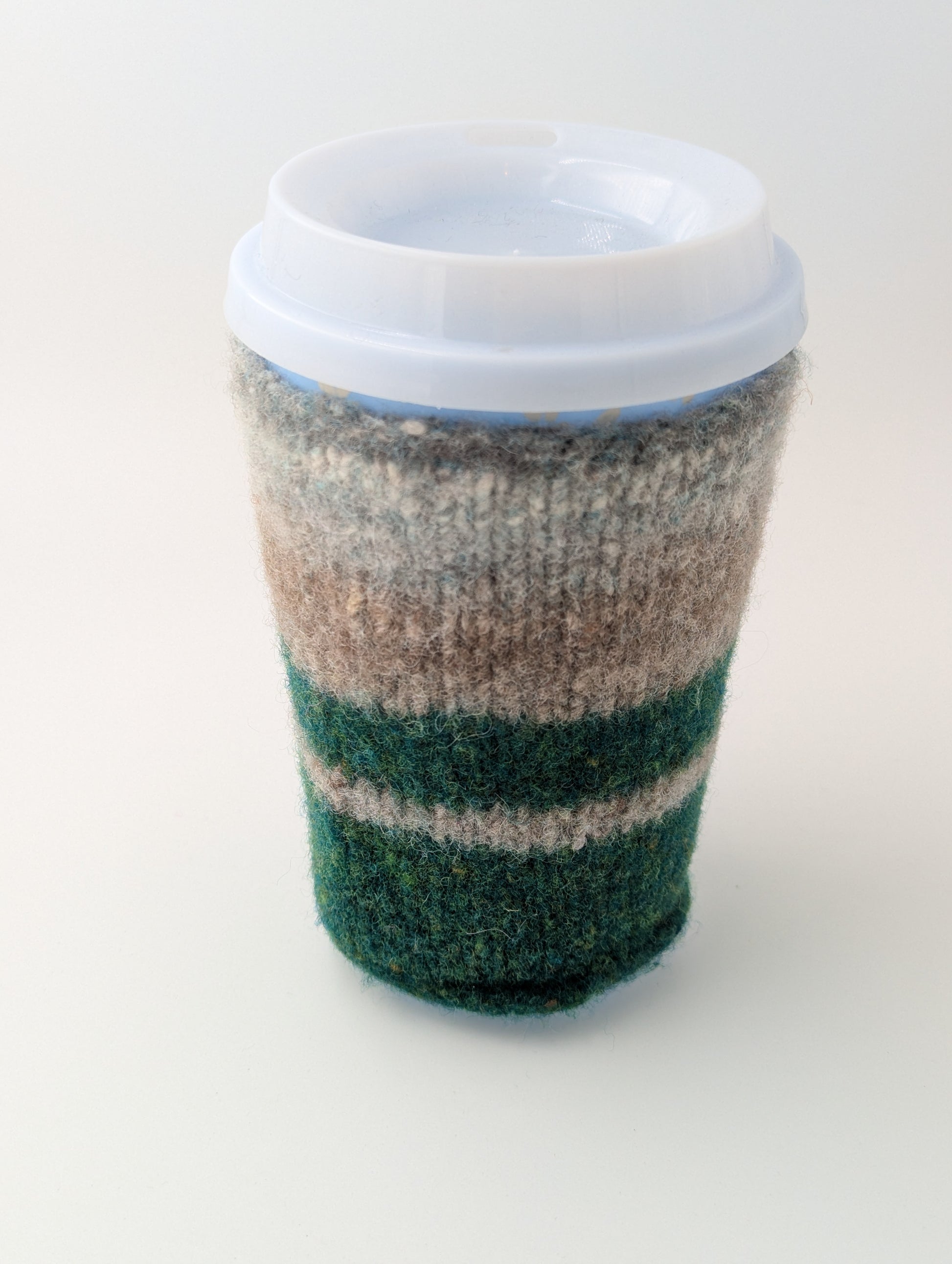 Knitted and felted mug cozy in shades of beige, grey, and green